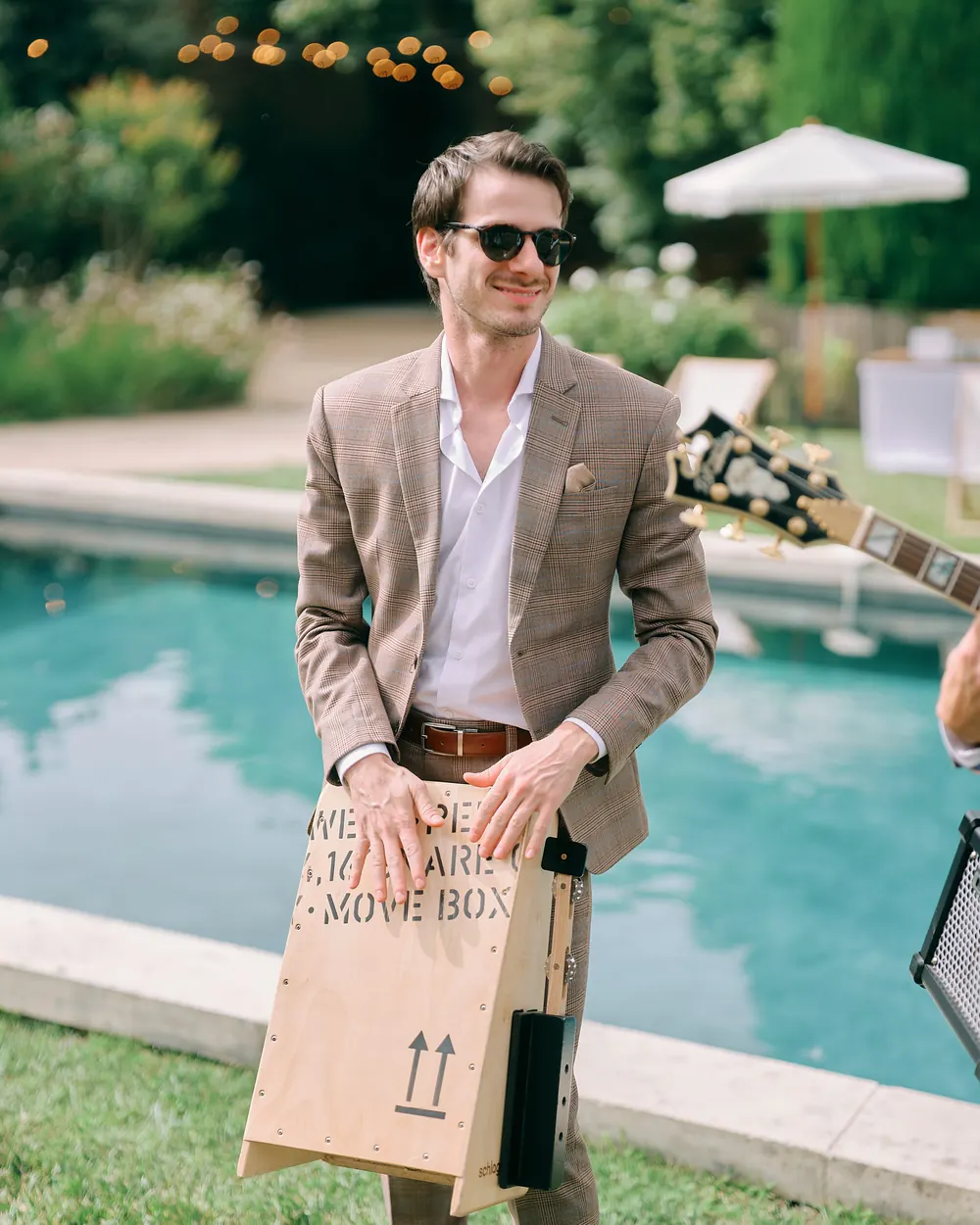A musician with the cajon box by a pool