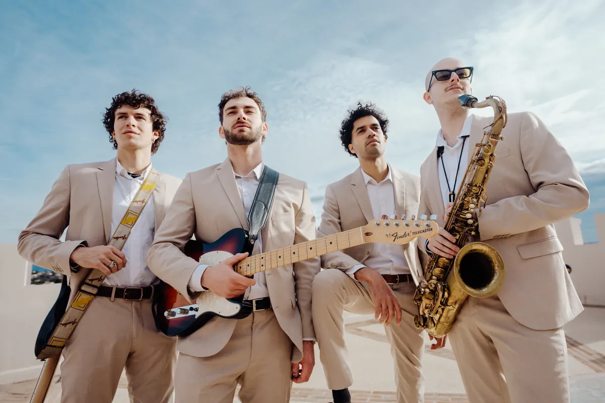 The quartet with guitars and saxophone against the sky