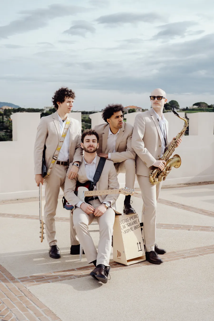 The band seated in a courtyard, saxophone raised