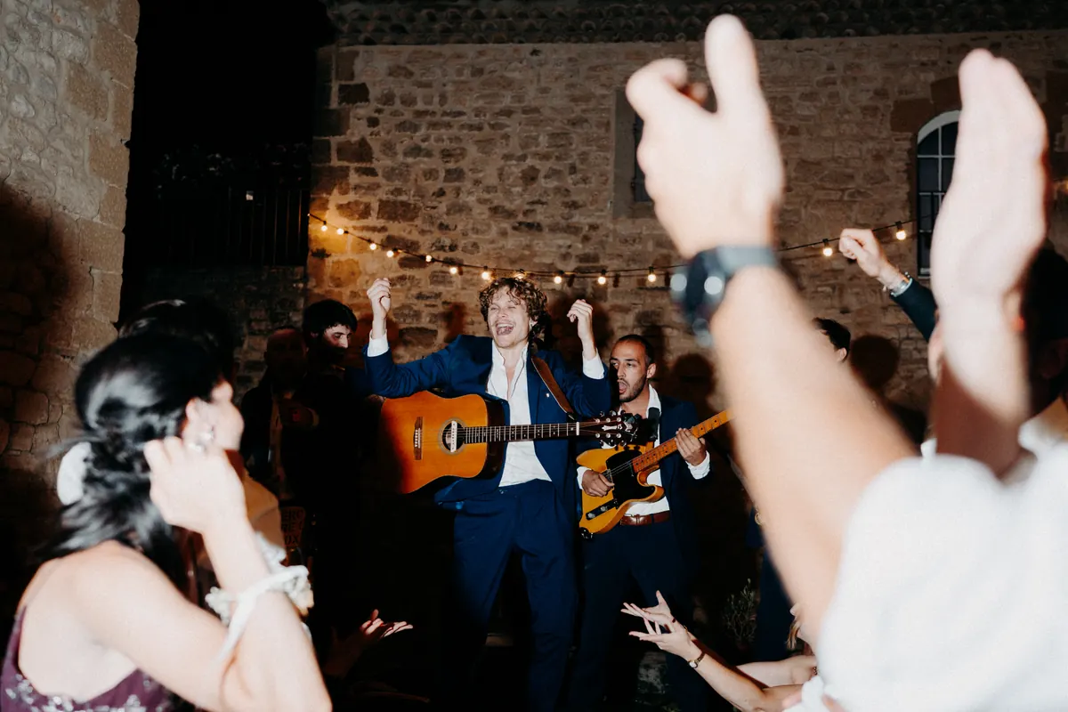 Guests singing along on a stone terrace at night