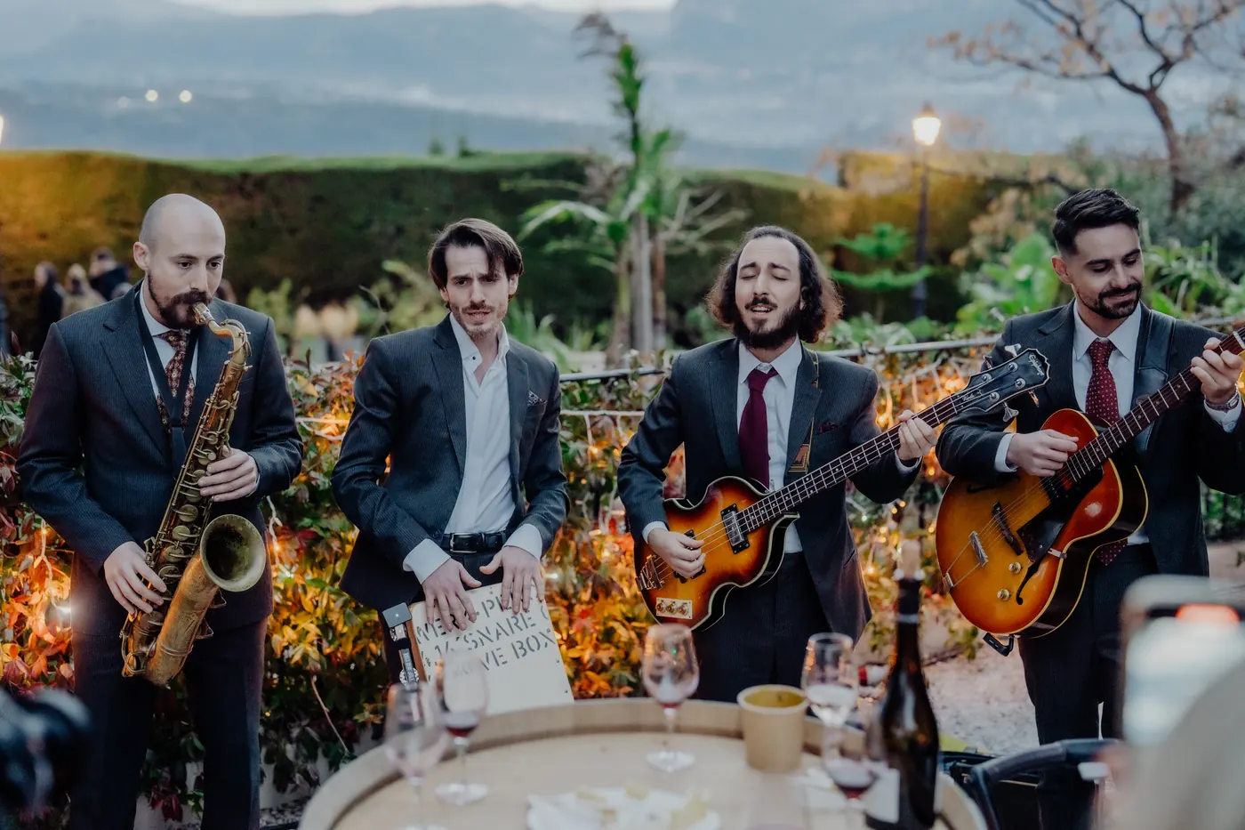 The band playing to a dinner table in a garden at dusk