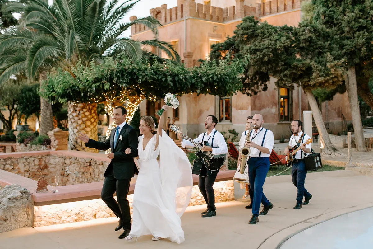 The couple dancing among palm trees with the band