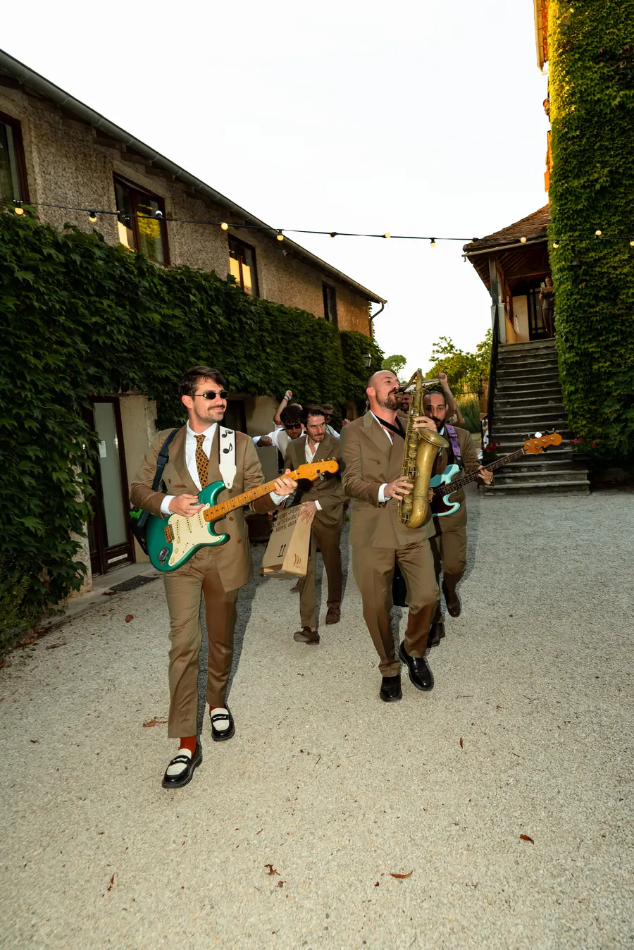 Guitarist and guests dancing down a village lane
