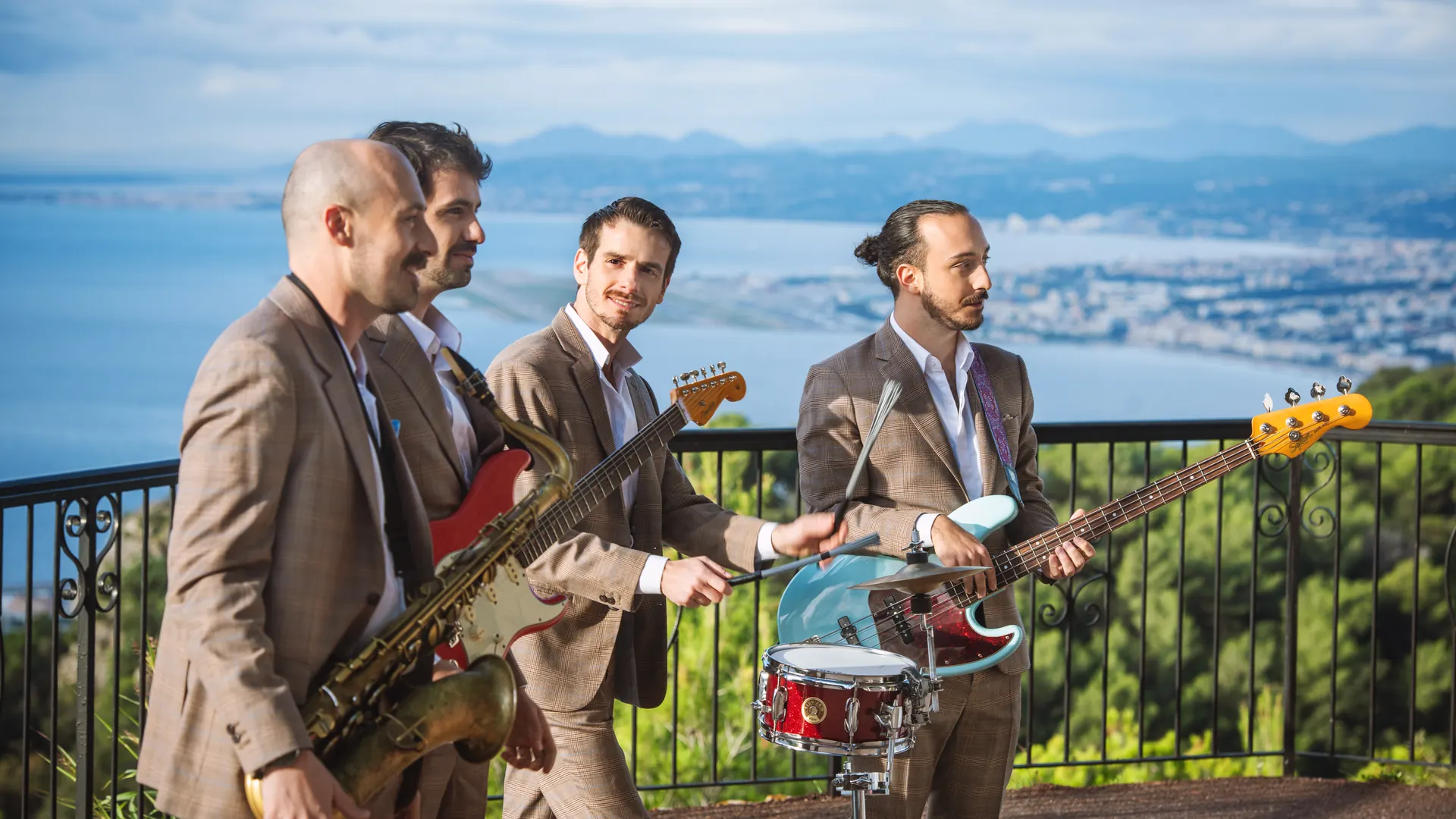 The band on a terrace overlooking the bay at golden hour