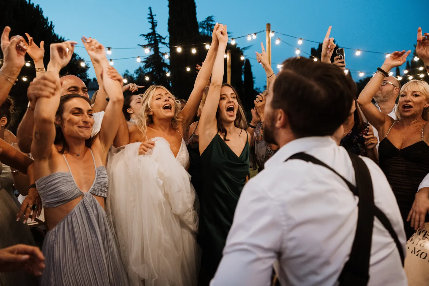 A full dancefloor under string lights at blue hour