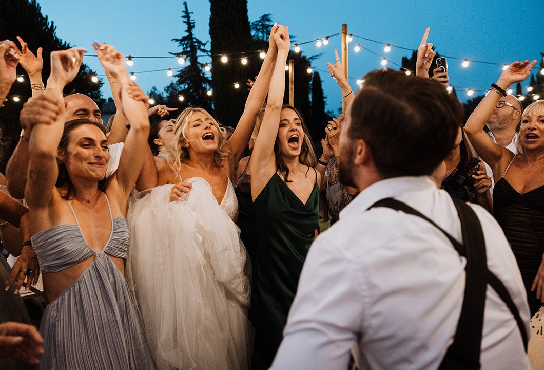 Guests dancing under string lights at blue hour