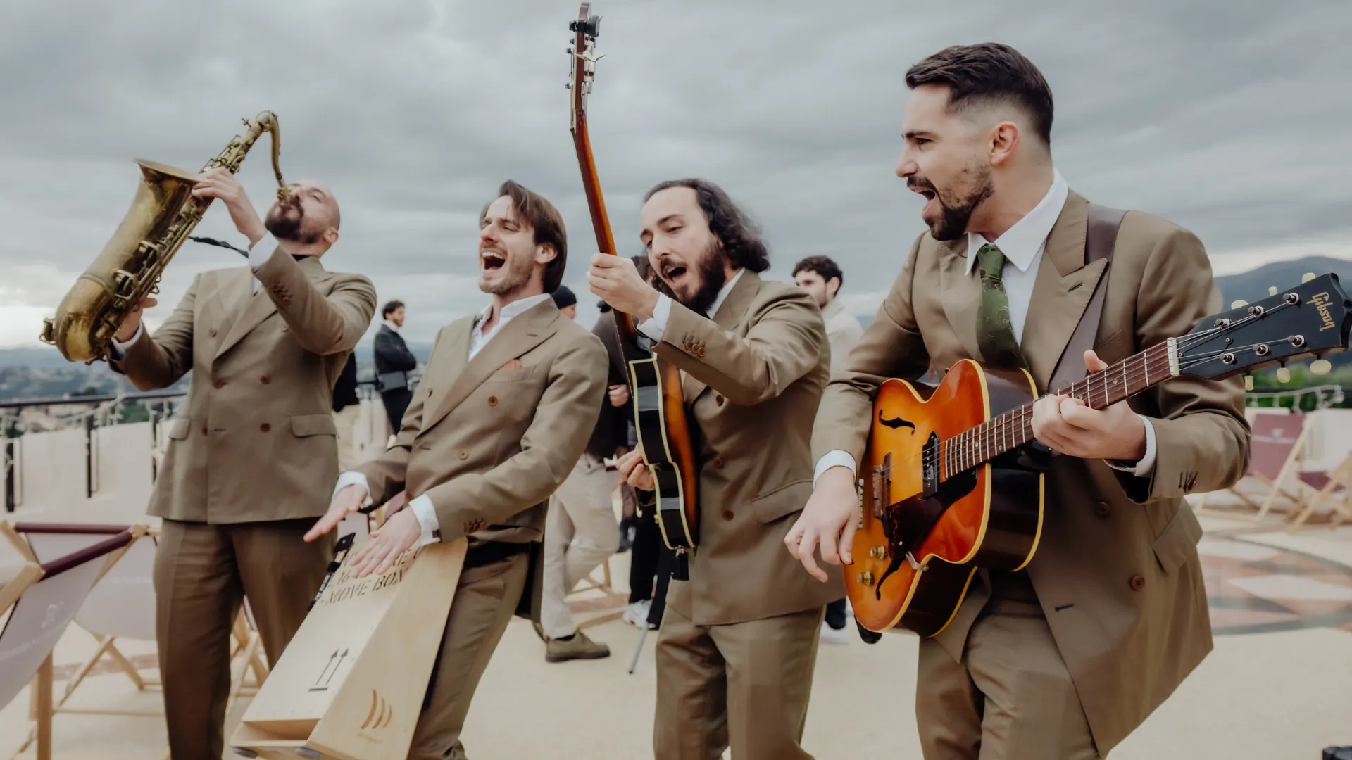 The band walking along a seafront terrace, saxophone leading