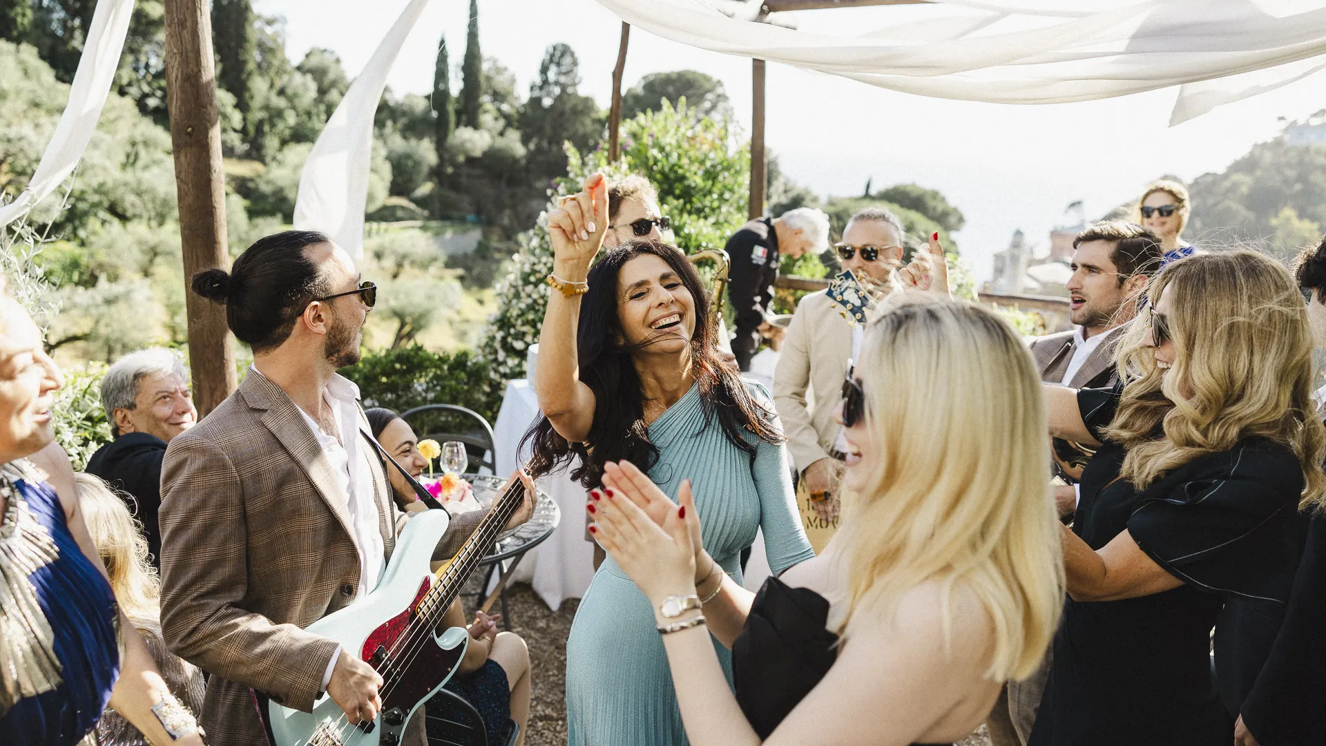 Guests clapping and dancing around the band under a white canopy
