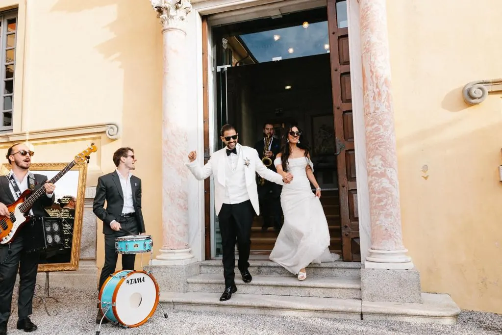 The couple leaving the ceremony as the band plays at the door
